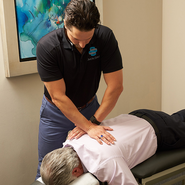 Therapist fixing patient's shoulders and back